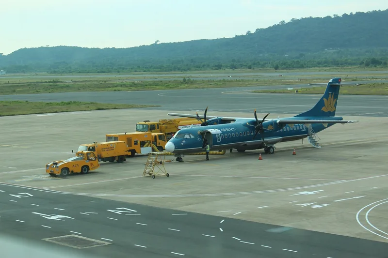 Máy bay cánh quạt ATR72 của Vietnam Airlines đậu trên đường băng sân bay Phú Quốc cùng các xe phục vụ mặt đất.